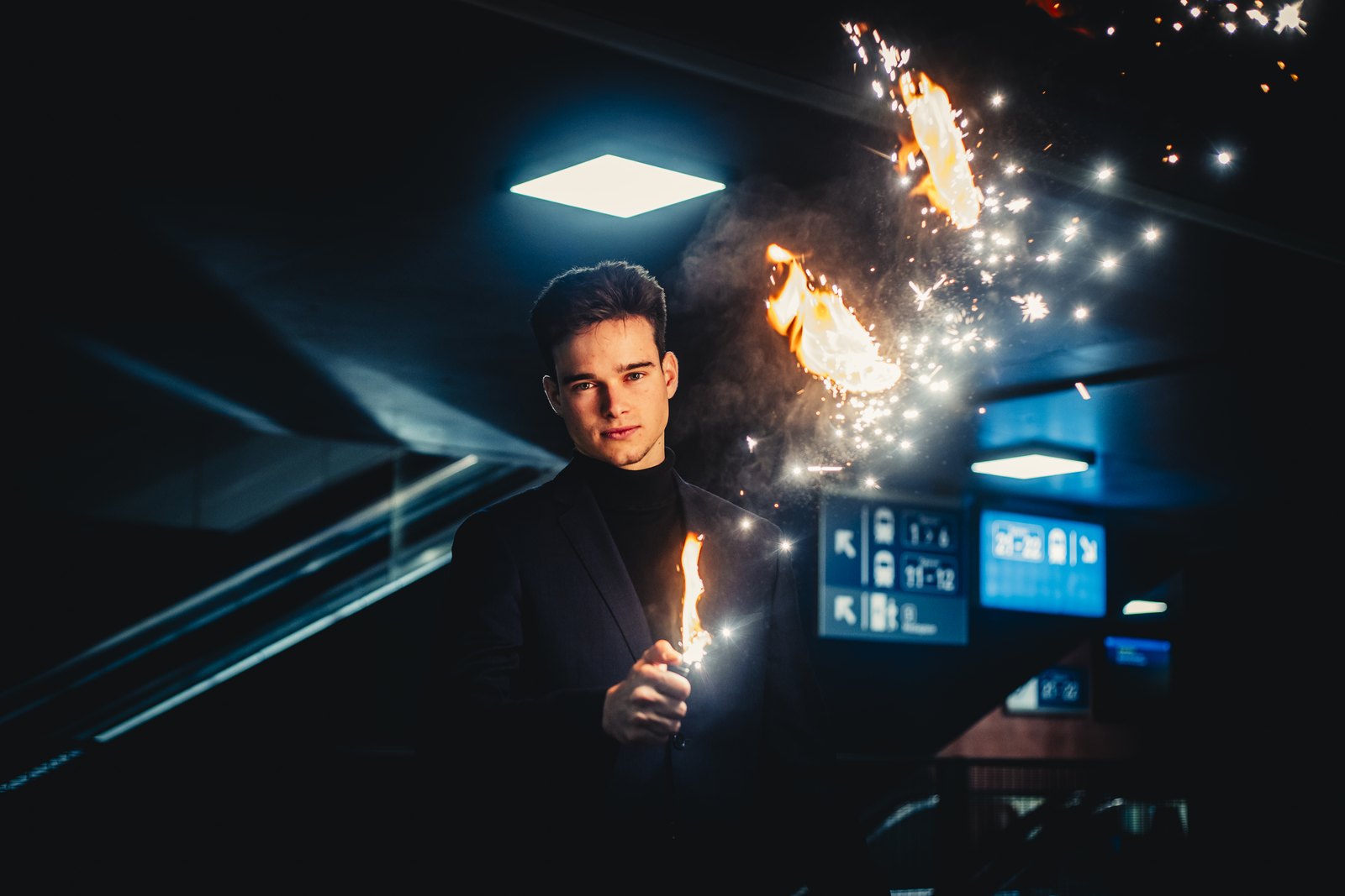 Jonas De Bruyn holding a flame, sparks lighting up the dark behind him