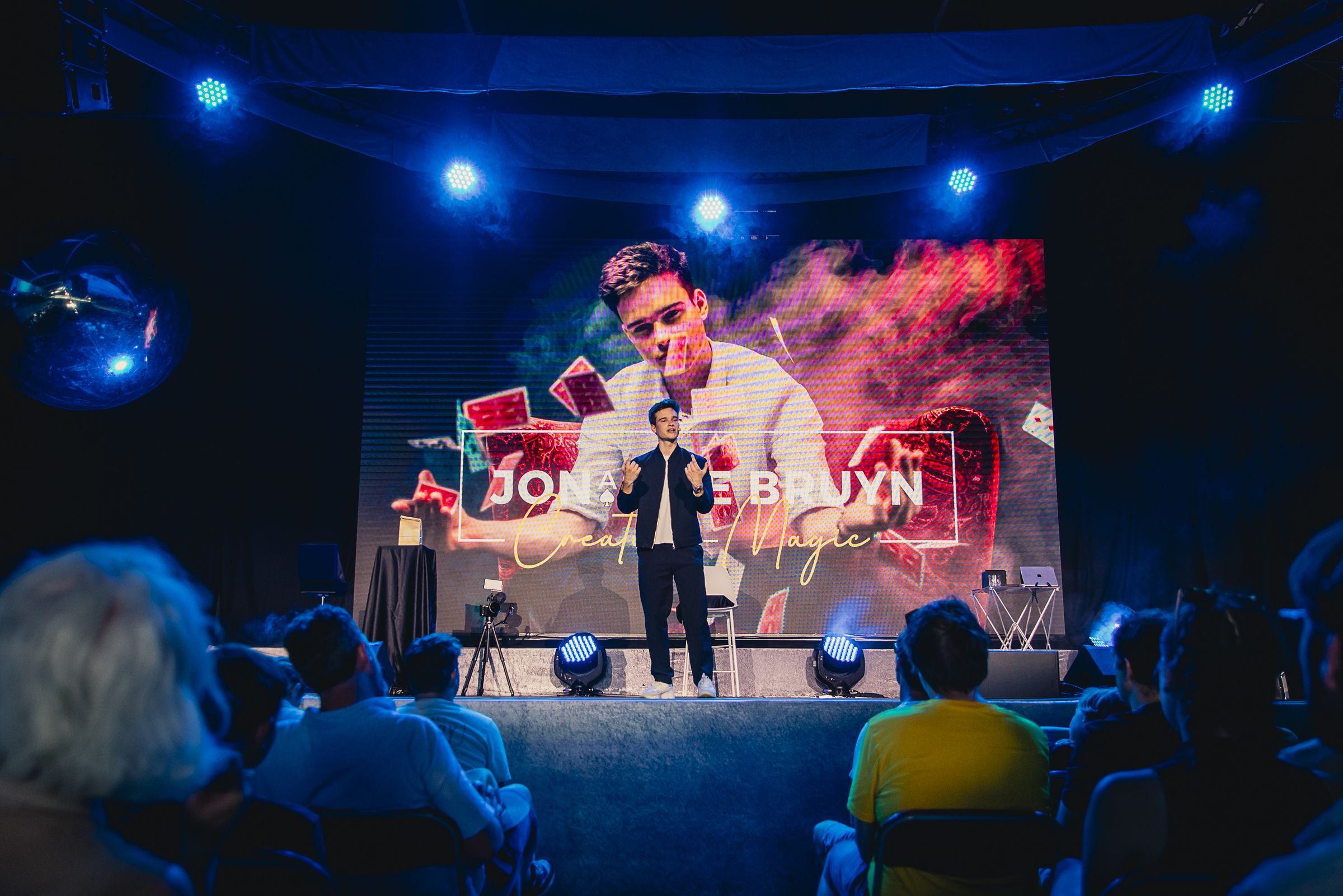Jonas De Bruyn hosting on a stage with a large LED screen behind him