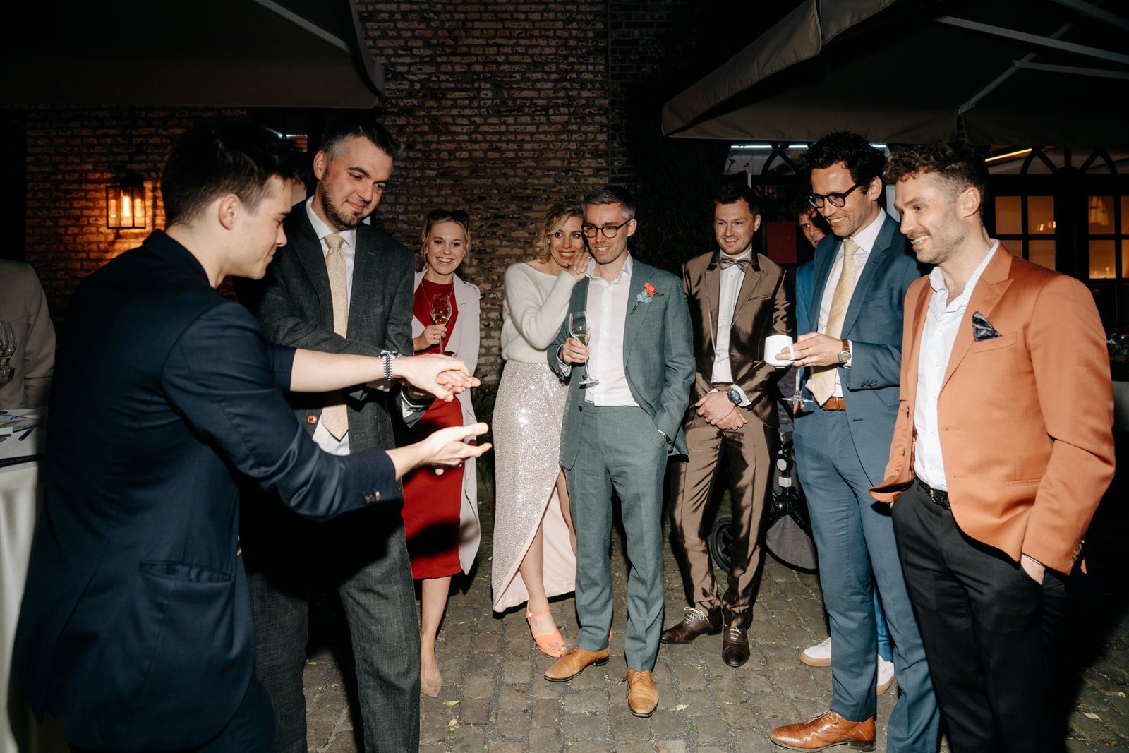 Jonas De Bruyn performing close-up magic for a group of guests at an elegant evening gathering