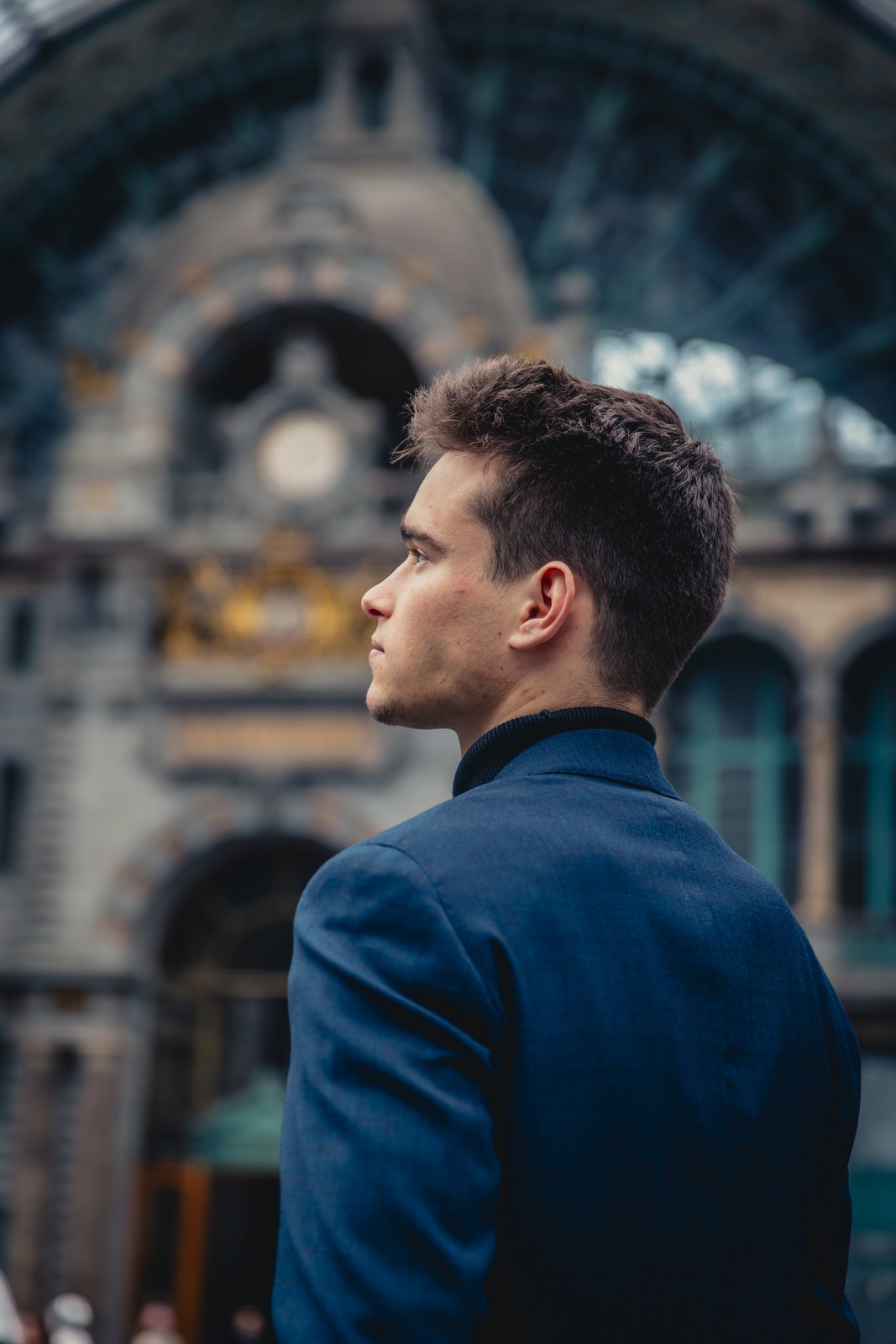Jonas De Bruyn in profile, a quiet portrait in front of a historic station facade