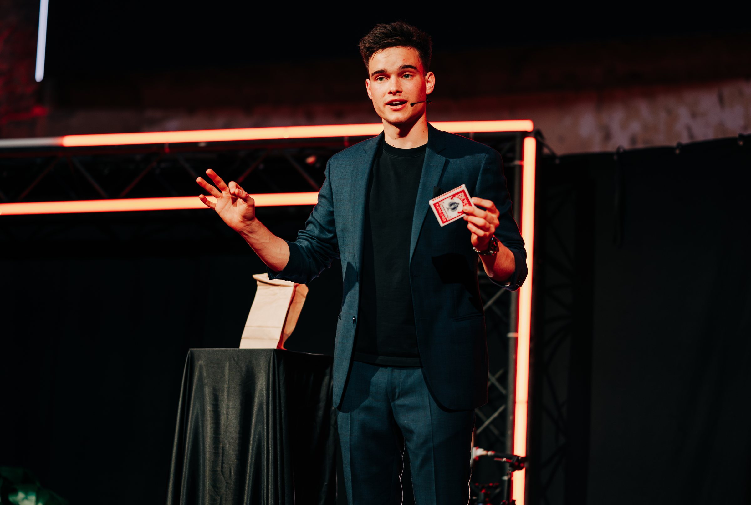 Jonas De Bruyn revealing a playing card on stage at a product launch event